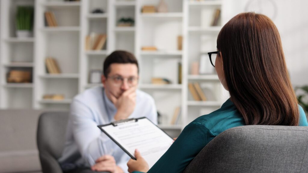 Médica com residência em psiquiatria atendendo paciente em consultório.